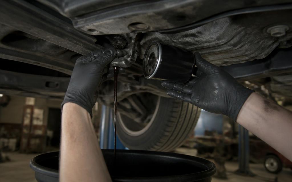 Fresh engine oil being poured during a car service with a new oil filter in hand